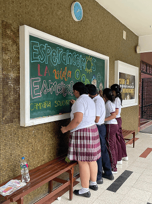 Estudiantes de bachillerato presentando un debate en un auditorio moderno.